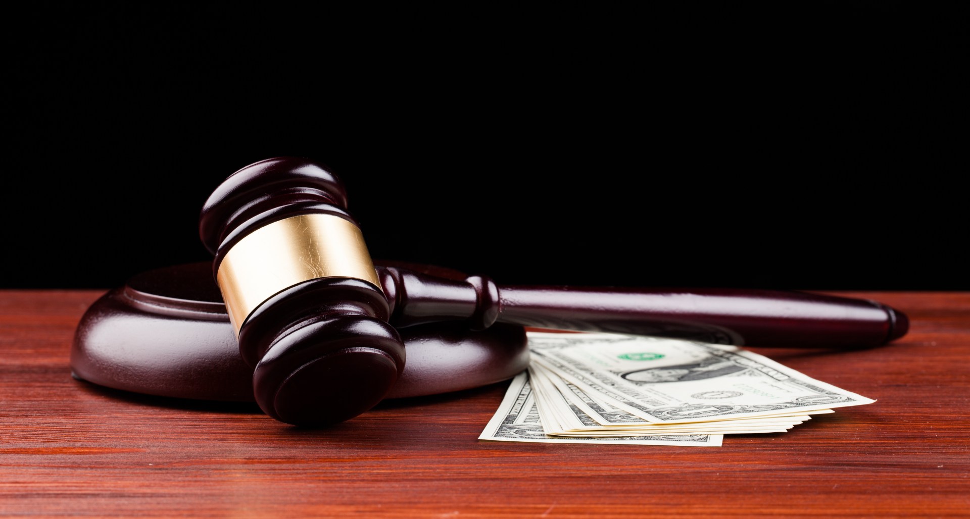 Gavel and cash on wood surface with black background